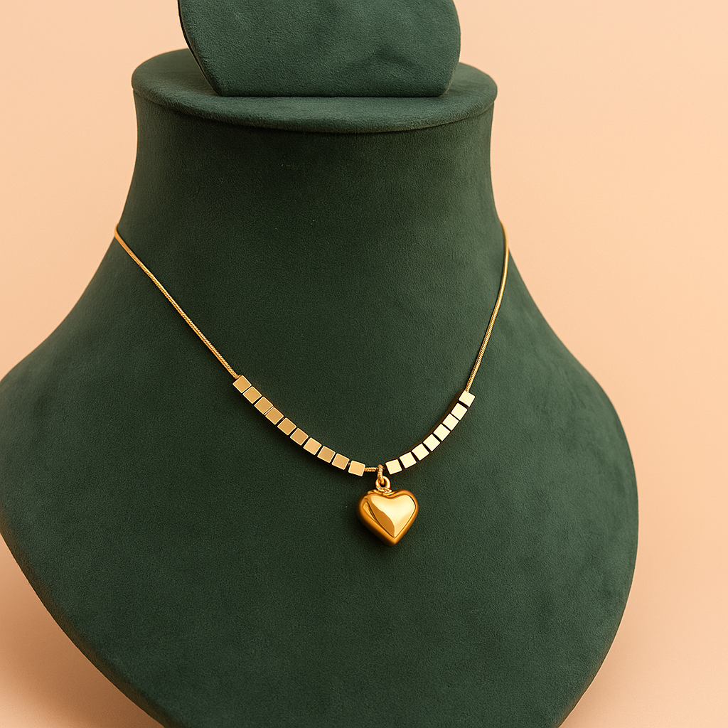 Gold necklace with a heart pendant on a green mannequin bust against a beige background