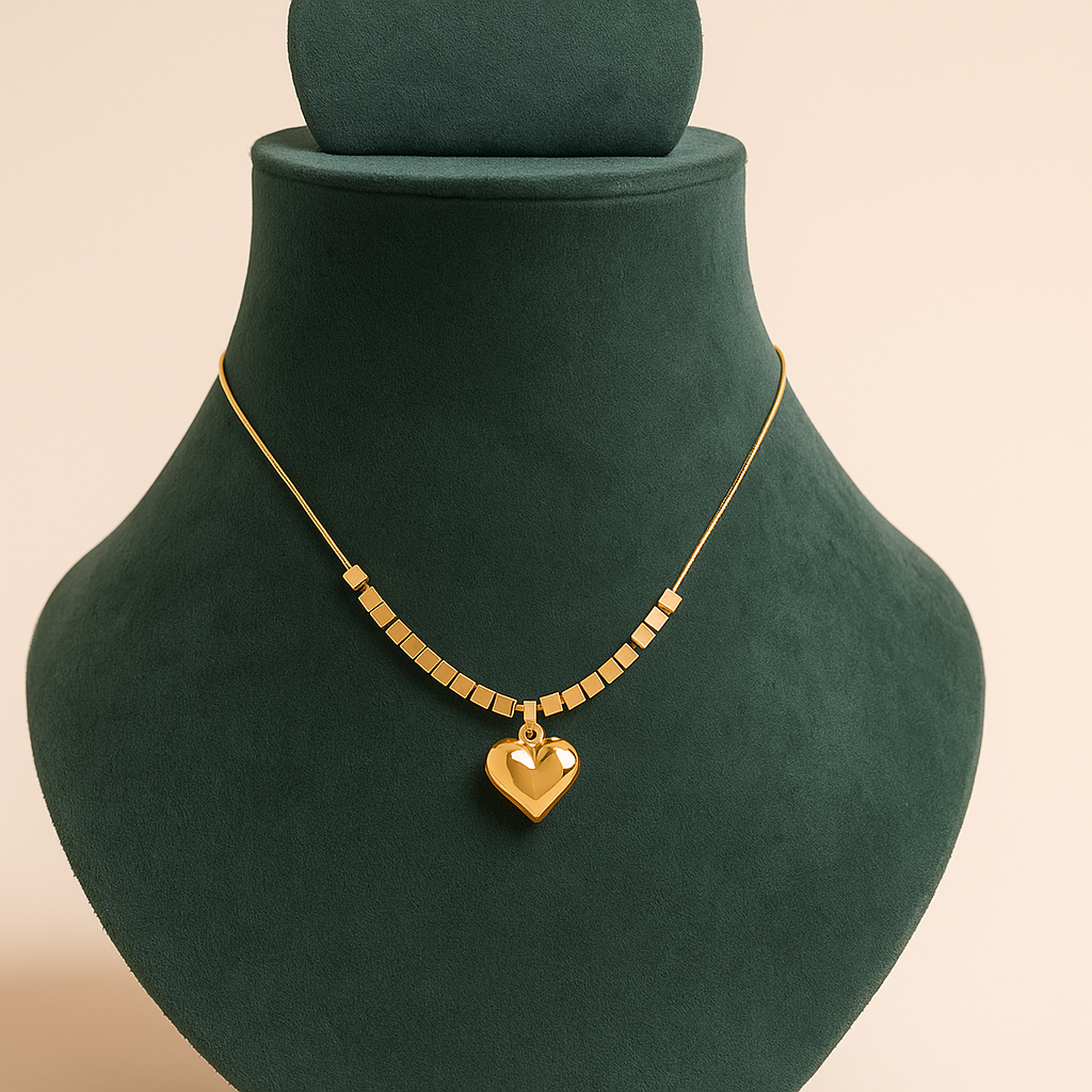 Gold necklace with a heart pendant on a green velvet stand.
