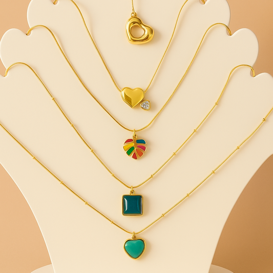 Set of gold necklaces with colorful pendants on a white stand against a beige background